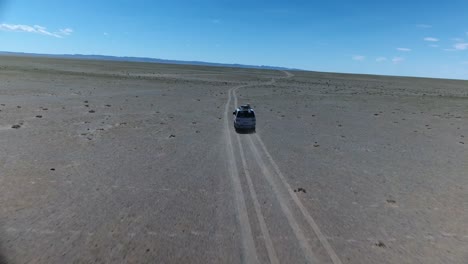 Aerial-drone-shot-following-a-van-in-gobi-desert
